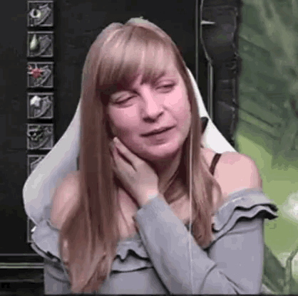 a woman is sitting in a chair with her eyes closed and her hand on her face .