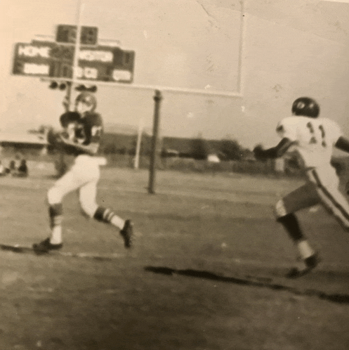 a black and white photo of a football game with a scoreboard that says home