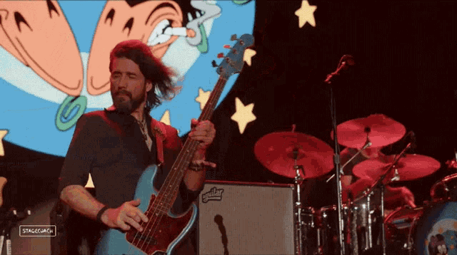a man playing a bass guitar in front of a stagecam sign
