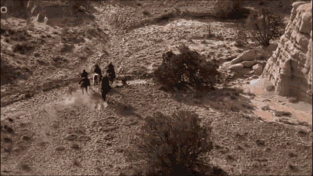 a group of people are riding horses through a desert