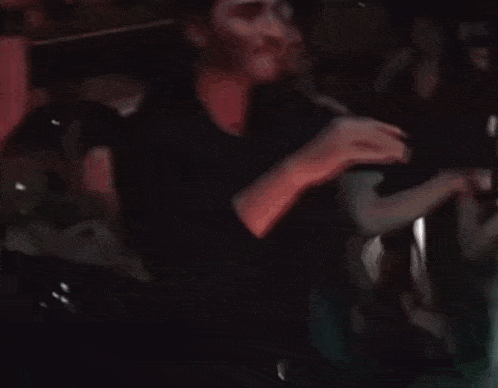 a man in a black shirt is dancing in a dark room .