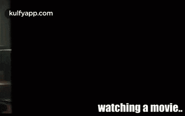 a man is sitting on the floor watching a movie on a laptop computer .