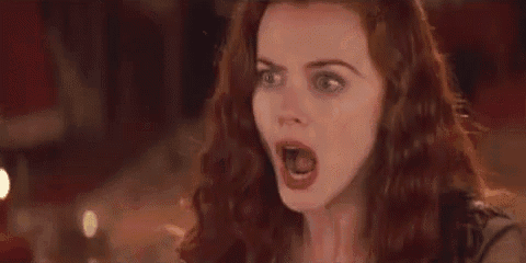 a woman with red hair is covering her mouth with her hand and making a surprised face .
