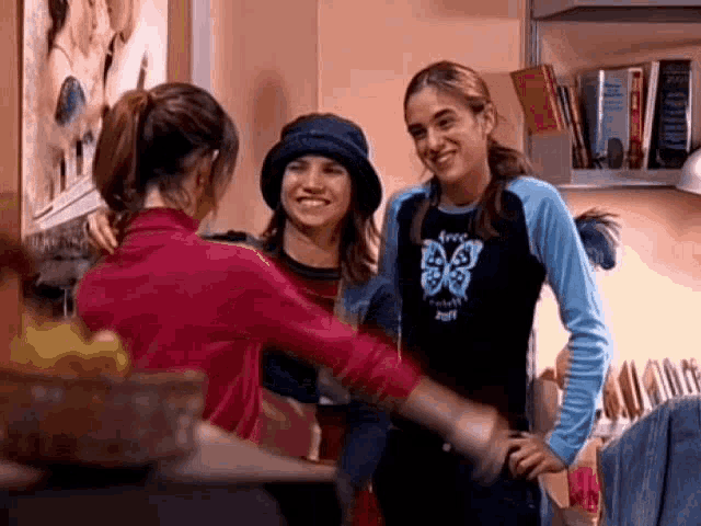 a girl wearing a shirt with a butterfly on it is hugging two other girls .