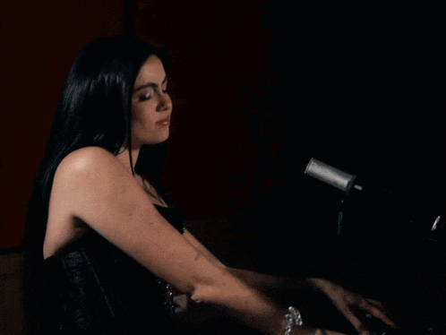 a woman is singing into a microphone while playing the piano