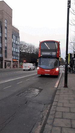 a red double decker bus with the number 222 on the front is driving down a street