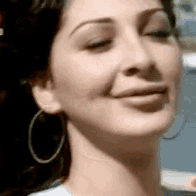 a close up of a woman wearing hoop earrings and smiling .