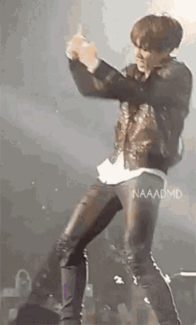 a man in a leather jacket and leather pants is standing on a stage .