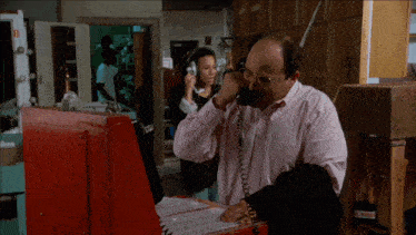 a man in a pink shirt is talking on a phone with a woman