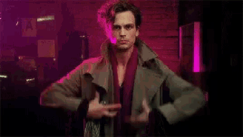 a man is standing in a dark room holding a jacket and a sword .