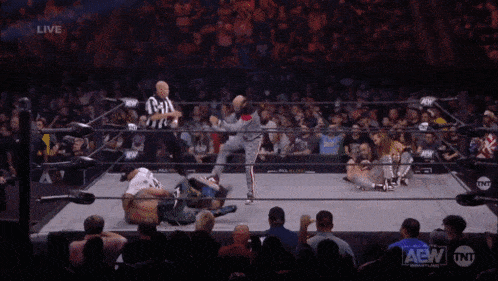 a wrestler is laying on the ground during a live aew match