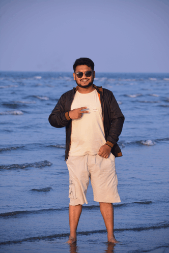 a man wearing sunglasses and a white shirt that says ' abercrombie & fitch ' on it stands on the beach