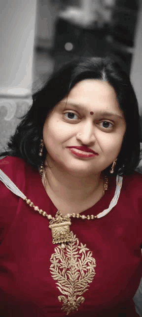 a woman with a red dot on her forehead wears a gold necklace
