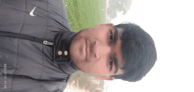 a young man wearing a nike jacket takes a picture of himself