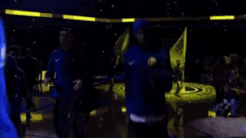 a man in a blue hoodie is walking in a dark room with other people .