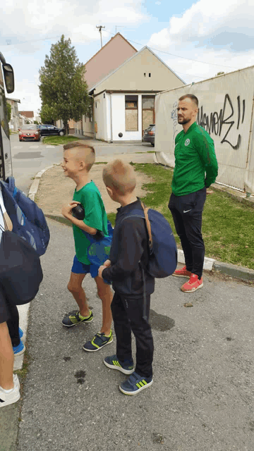 a man in a green jacket is standing next to a boy in a green shirt