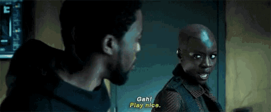 a man and a woman are standing next to each other in a dark room . the woman is saying `` play nice '' .