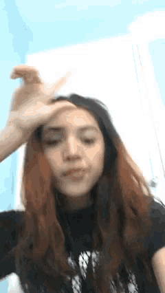 a girl with long hair is making a funny face with her hand on her forehead