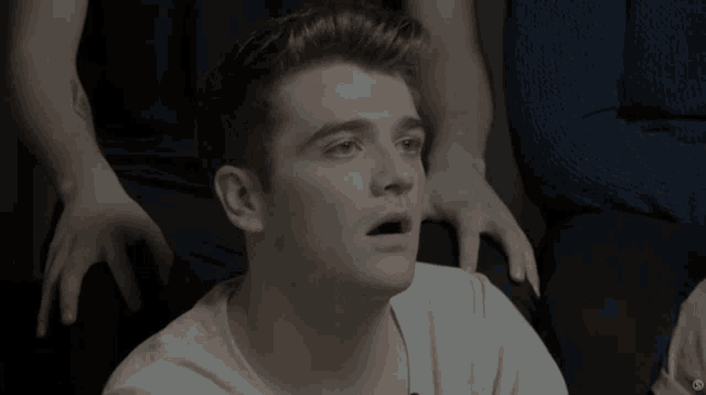 a young man with his eyes closed is surrounded by other men