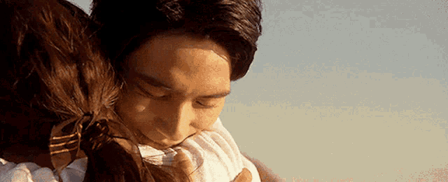 a man and a woman are hugging each other and the woman is kissing the man 's face .