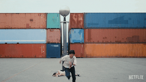 a man running in front of a stack of shipping containers with netflix on the bottom