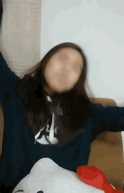 a girl is making a funny face with her arms outstretched and a hello kitty pillow behind her