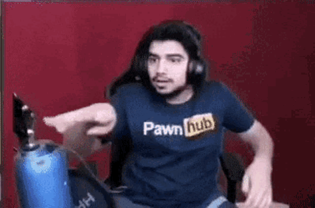a man wearing a blue pornhub shirt is sitting in front of a microphone .