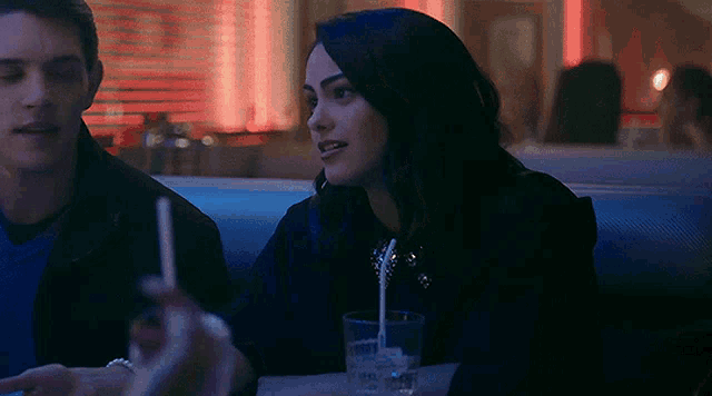 a man and a woman are sitting in a diner at night .