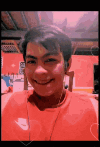 a young man wearing headphones and a red nike shirt smiles for the camera
