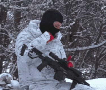 a man wearing a black mask is holding a gun in the snow
