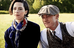 a man and a woman are sitting next to each other on a bench in a field .
