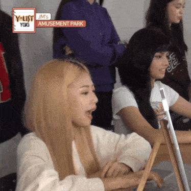 a group of girls are sitting in front of a sign that says jm 's amusement park on it