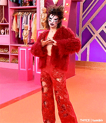 a woman in a red fur coat and red pants is standing in front of a pink wardrobe .