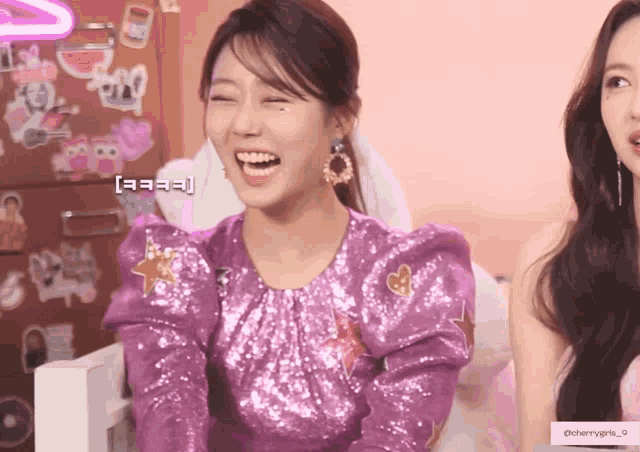 a woman in a purple sequined top is laughing with another woman
