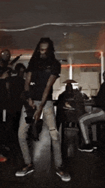 a man with dreadlocks is dancing in a room with a group of people .