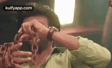 a man is holding a chain around his neck and covering his face .
