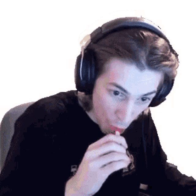 a man wearing headphones is eating a lollipop while looking at the camera .