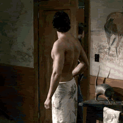 a shirtless man with a towel around his waist is standing in a room .