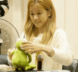 a woman is holding a green stuffed frog in her hands .