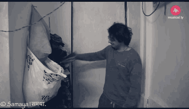 a black and white photo of a man standing next to a laundry bag that says wash