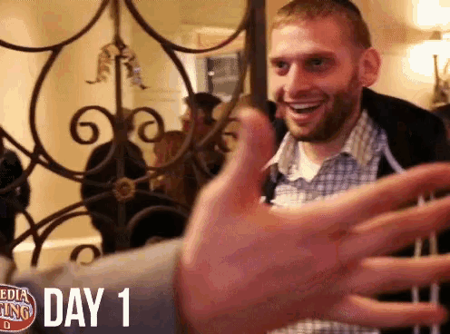 a man 's hand is reaching out in front of a wrought iron gate that says day 1 on it