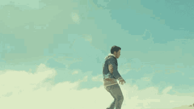 a man in a denim jacket is standing in the desert