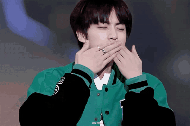 a person wearing a green jacket with a ring on their finger
