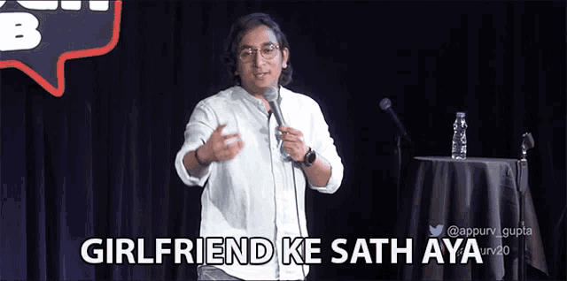 a man stands in front of a microphone with the words " girlfriend ke sath aya " above him
