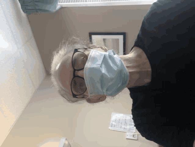 a man wearing a face mask and glasses is standing upside down