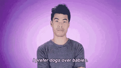 a man is standing in front of a purple background and saying `` i prefer dogs over babies . ''