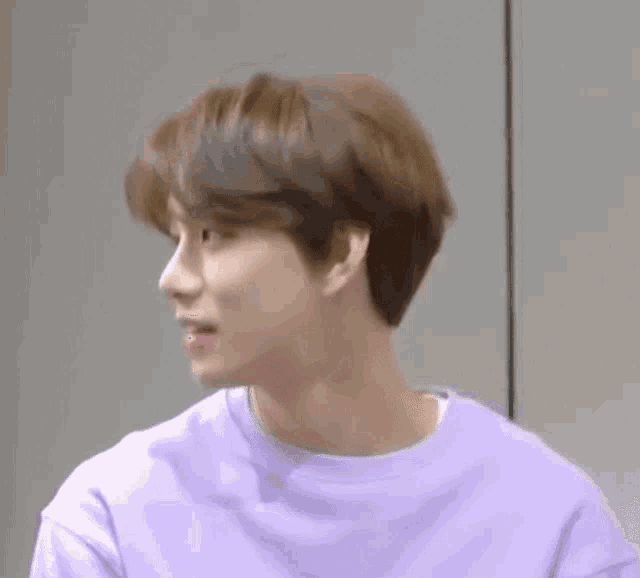 a young man in a purple shirt is looking to the side .