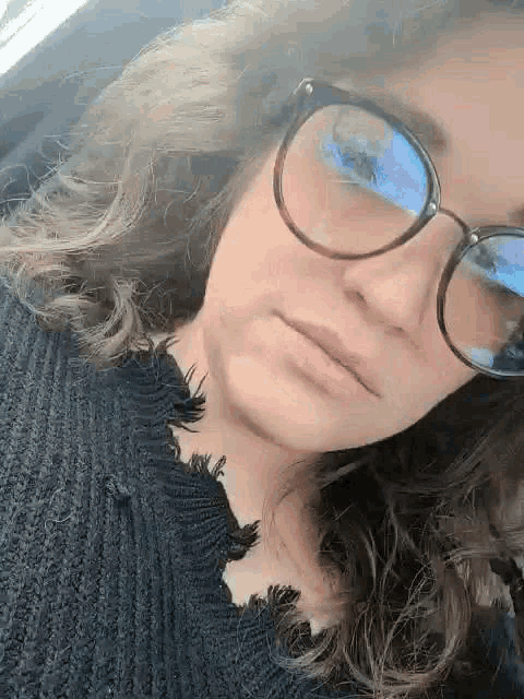 a close up of a woman wearing glasses and a black sweater