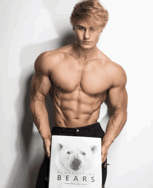 a shirtless man holds up a book titled remembering bears