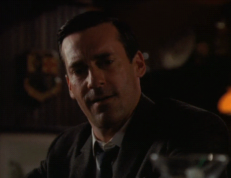 a man in a suit and tie is sitting at a table with a martini glass